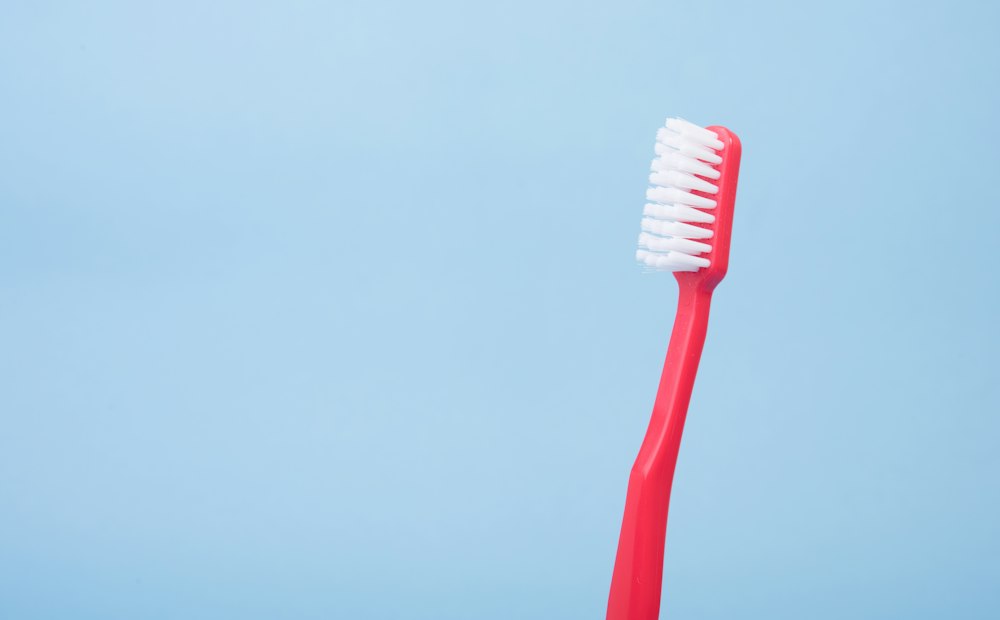 Cepillo de dientes rojo sobre fondo celeste