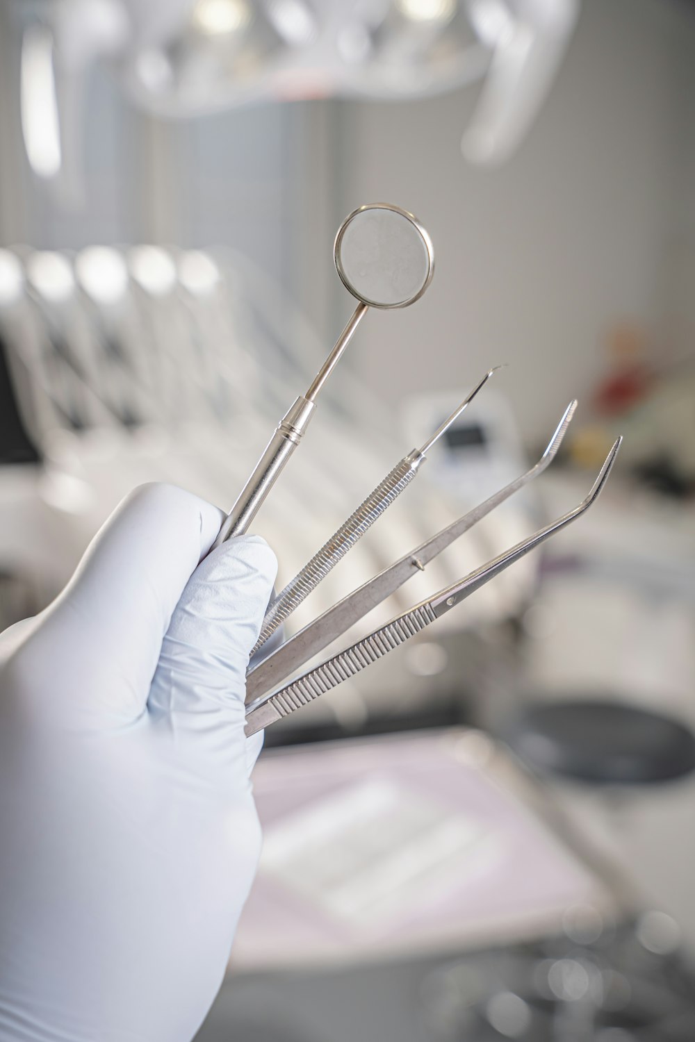 Mano con guante sosteniendo instrumental dental